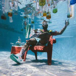 black man underwater in pool wearing nikes