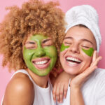 young women having green facial mask beauty treatment